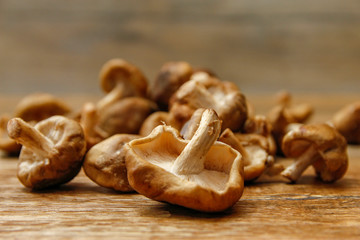 Fresh shiitake mushroom on wooden table, close-up photo in rustic ambient with low light
