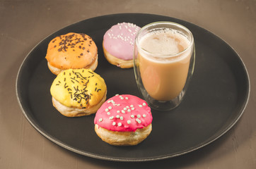 donuts in glazes and a glass of a cappuccino/donuts in glazes and a glass of a cappuccino on a black tray