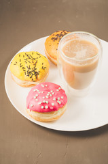 donuts in glazes and a glass of a cappuccino/donuts in glazes and a glass of a cappuccino on a white tray