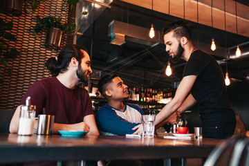 Multiracial men meeting their friend in lounge bar. Real emotions of best friends happy to see each other. Friendship