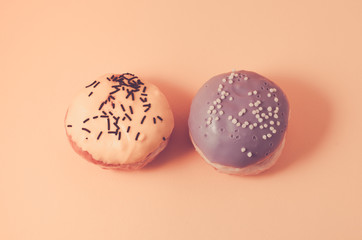 donuts isolated on pink background/Donuts in glaze decorated with dark chocolate sticks and balls on pink background, top view