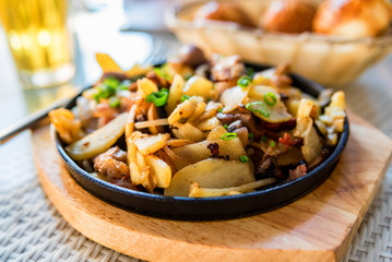 Roasted potato in frying pan with meat and green leek