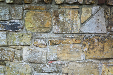 A close-up of a stone wall in random geometric shapes and sizes with a weathered finish. Rustic textured background or flat lay concept.