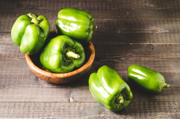 Fresh green organic paprika on wooden bowl/Fresh green organic paprika on wooden bowl over dark wooden background. closeup. Selective focus