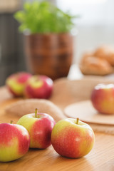 Close-up on red and green apples on wooden table in dining room interior with healthy food. Real photo