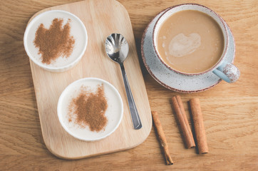 puddings with cinnamon in a white bowl and a cup of coffee/puddings with cinnamon in a white bowl and a cup of coffee on a wooden background. Top view