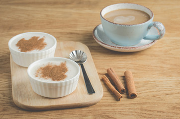 two puddings with cinnamon and a cup of coffee/two puddings with cinnamon and a cup of coffee on a wooden background. Selective focus