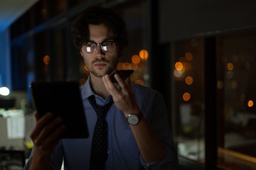 Male executive talking on mobile phone while using digital