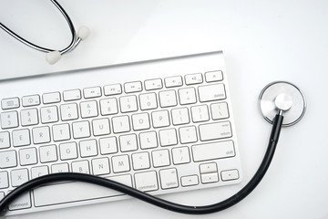 Adoption of technology in healthcare industry concept. Stethoscope and keyboard on white background. Flat lay or top view.  