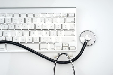 Adoption of technology in healthcare industry concept. Stethoscope and keyboard on white background. Flat lay or top view.  