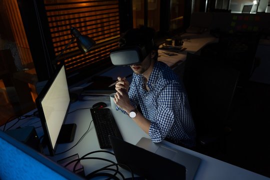 Young man using virtual reality simulator in office