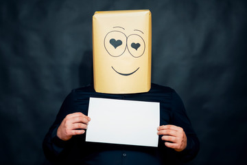 The concept of emotions. A man holds a blank white sheet in front of him. Looks lovers eyes. On the face smile.