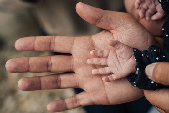 Comparing the size of a father's hand to his newborn baby's hand