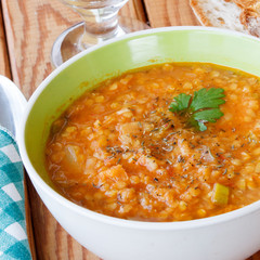 Bowl of red lentil soup served on wooden table