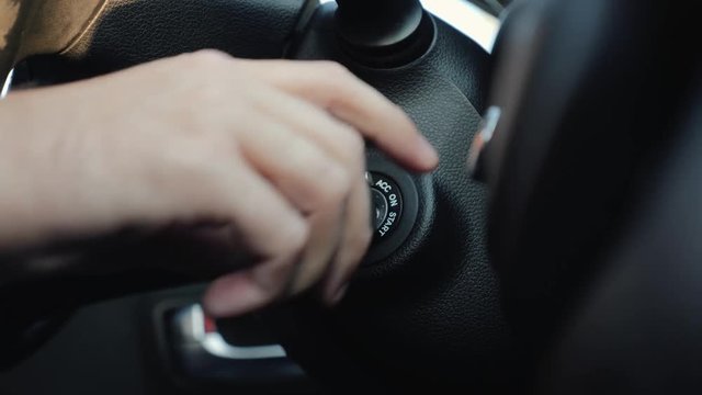The man inside the car hand holds the key in the ignition, start the car engine