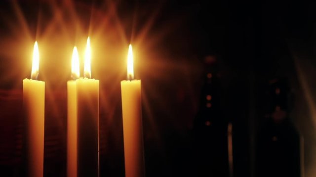 Christmas feeling with candles.  Close up on burning candles moving slowly in a circle. In background a basket and some bottles. Soft and star filters used in shooting.
