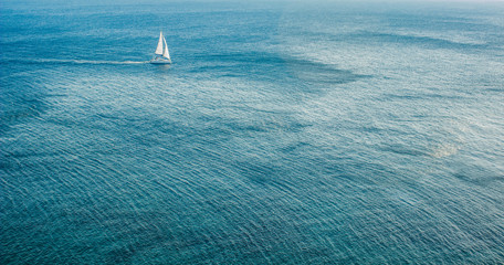 high aerial wallpaper shot of white yacht on south tropic sea water surface background landscape, copy space 
