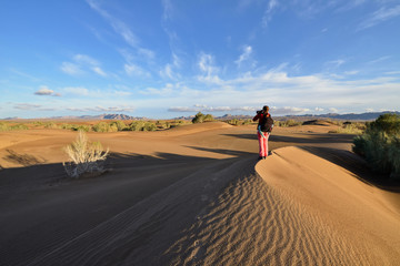 Fototapeta na wymiar Tourist on the orange sand dunes by the Mesr oasis on the Dasht-e Kavir desert near Khur city