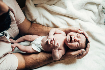 Father holding crying newborn baby