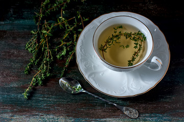 Obraz na płótnie Canvas Cup of herbal tea with thyme on a wooden table