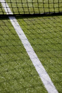 Green tennis court with net and white line marking