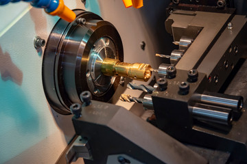 Fototapeta na wymiar The CNC lathe or turning machine cutting the thread at the brass shaft.Hi-technology manufacturing process.