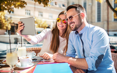 Young couple sitting in the cafe and having fun with tablet. Dating, relationships, love, romance, lifestyle, technology