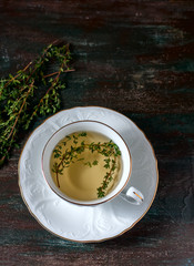 Cup of herbal tea with thyme on a wooden table