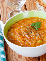 Bowl of red lentil soup served on wooden table