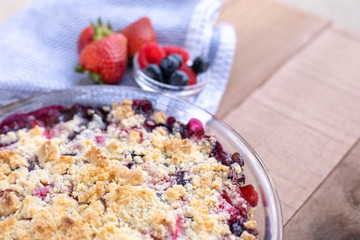 Close up on a homemade berry cobbler on a wood table, with space for text on top