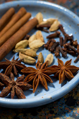 spices for masala tea in a blue plate, vertical