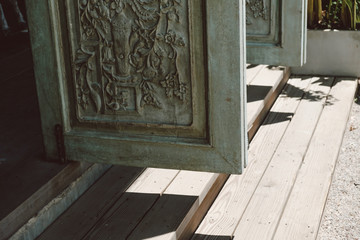 Retro style wooden door with flower sculpture with light and shadow from the sun