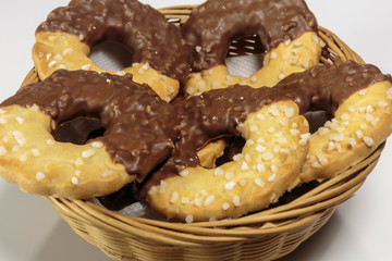 Basket with delicious ring-shaped chocolate chip cookies on a white background closeup.