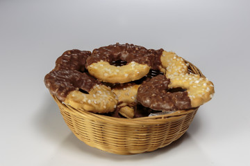 Basket with delicious ring-shaped chocolate chip cookies on a white background closeup.