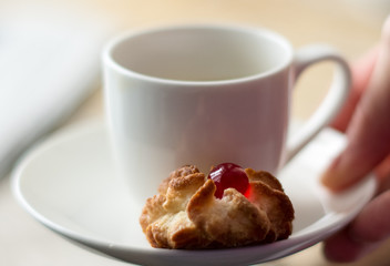 Porcelain white pot with little pastry on the saucer