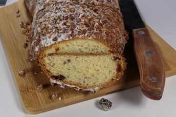 Pound cake with walnuts and raisins on a cutting board. Sprinkled by powdered sugar and crushed walnuts.