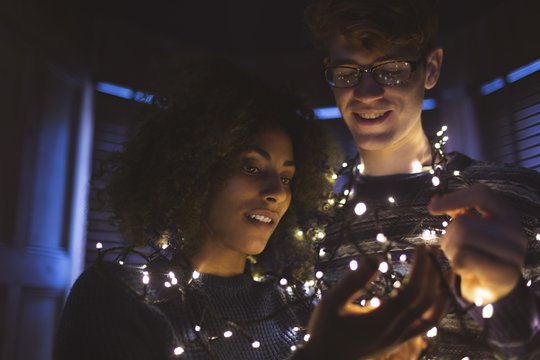 Couple playing with fairy lights at home