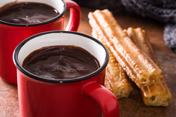 Hot chocolate with churros on wooden table.