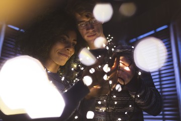 Couple playing with fairy lights at home