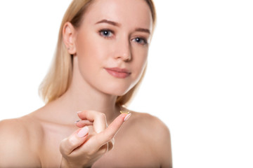 Focus on contact lens on finger of young woman. Young woman holding contact lens on finger in front...