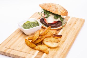 Fast food. Tasty burger with potato fries on a wooden board.
