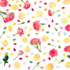 Roses flowers and petals with bright sugar candy on white background. Flat lay, top view.