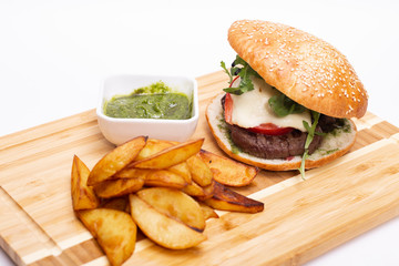 Fast food. Tasty burger with potato fries on a wooden board.
