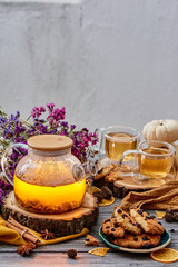 Transparent teapot, cookies with cranberries and two transparent cups of tea on wooden cuts and dried flowers on the background. Tea composition on wooden background. close-up. space