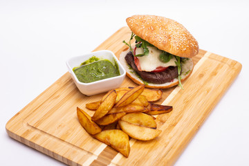 Fast food. Tasty burger with potato fries on a wooden board.
