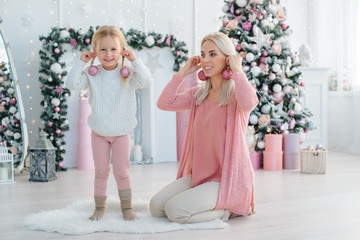 Merry Christmas Happy Holidays. mom daughter have fun background Christmas tree preparing for holiday. Parent little child having fun near Christmas tree indoors. Loving family with presents room.