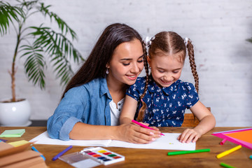 Happy family mother and daughter together draw with markers.