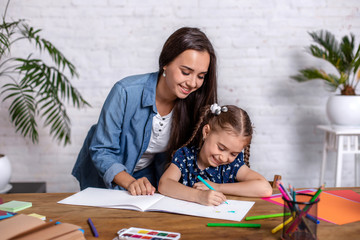 Happy family mother and daughter together draw with markers.