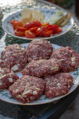 Raw pork and beef meat prepared for hamburgers on white rounded cutting board