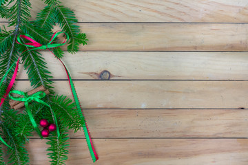 Greenery with  a ribbon bow, cinnamon sticks, and red berries  along left side border with copy space